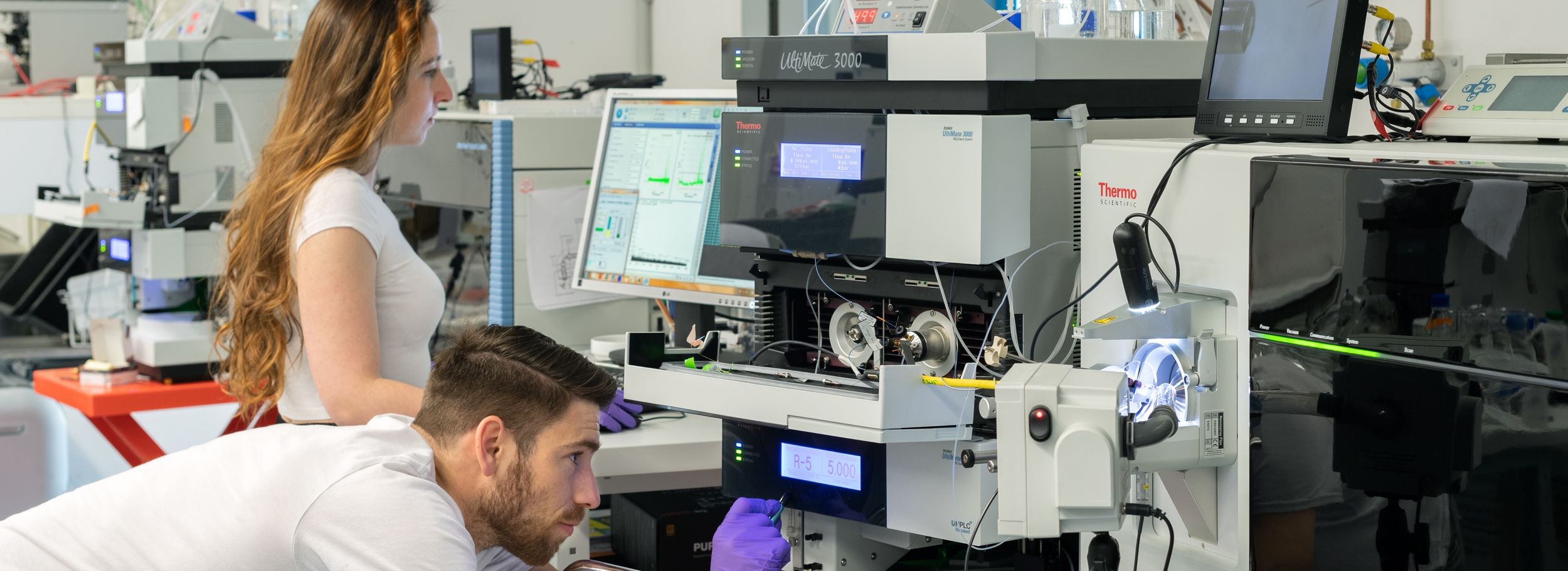 Two researchers working on a mass spectrometer