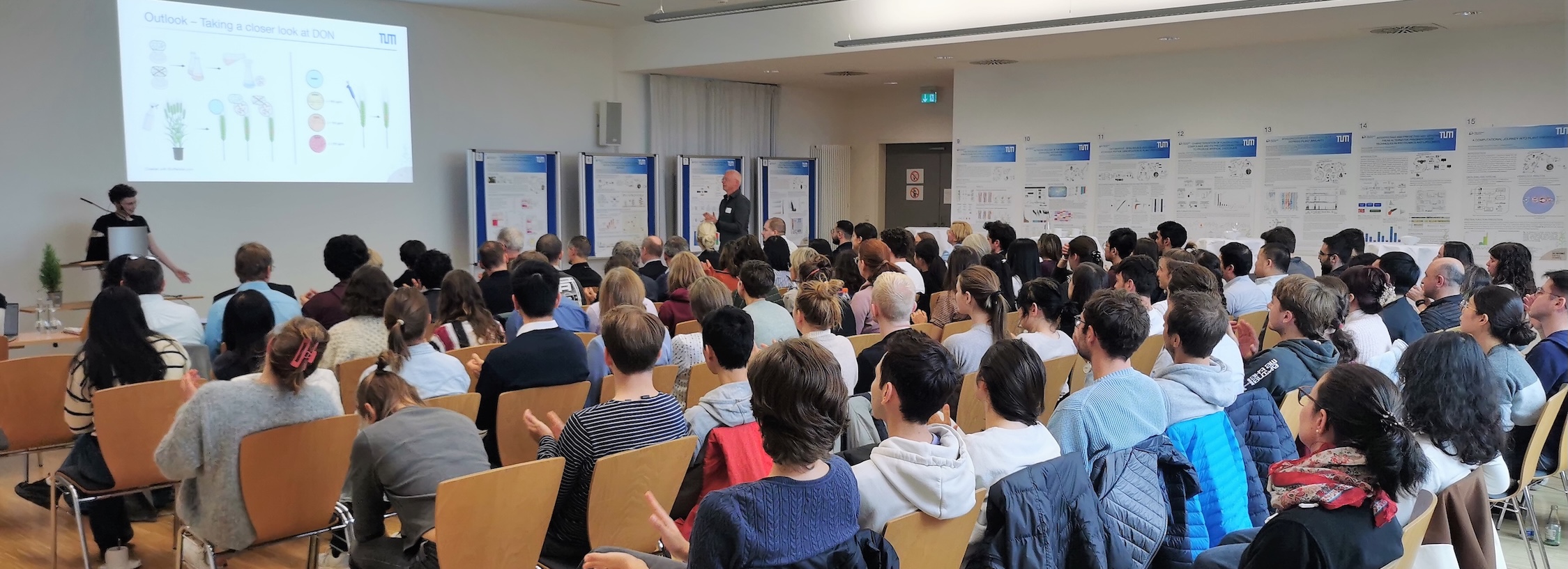 A room full of people listening to a scientific presentation